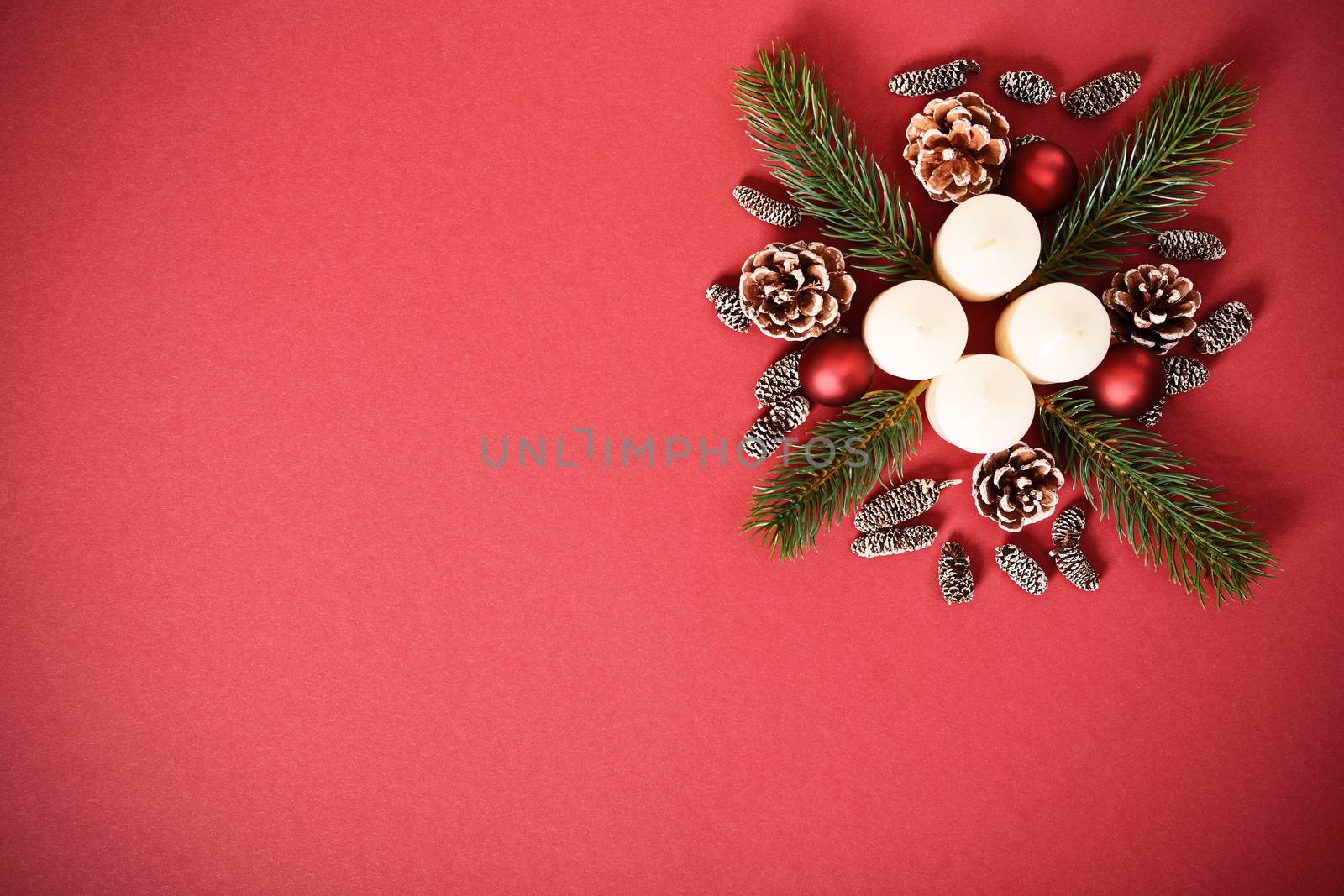 Christmas and New Year composition. Seasonal greeting card concept with white advent candles, evergreen branches and pinecones, on red background. Christmas, winter, new year concept. Flat lay, top view, copy space. 