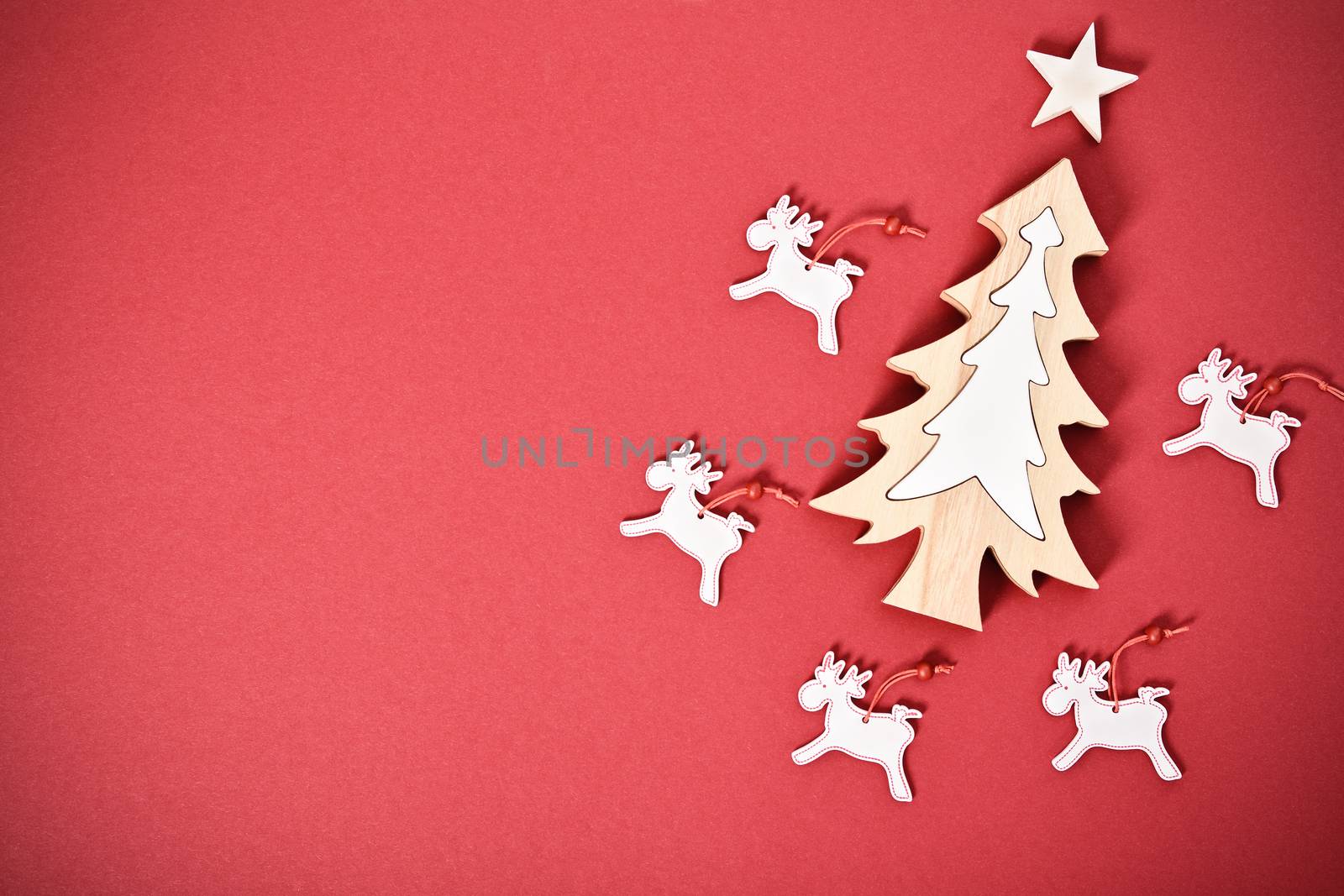Christmas and New Year composition. Seasonal greeting card concept with white Christmas tree, star and raindeers on red background. Christmas, winter, new year concept. Flat lay, top view, copy space. 