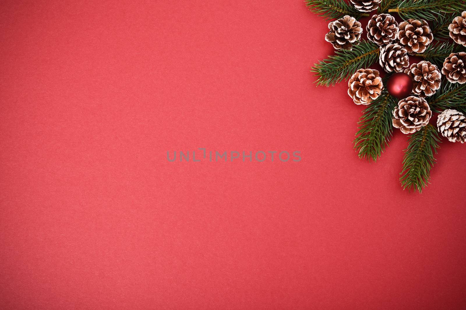 Christmas and New Year composition. Seasonal greeting card concept with pinecones and evergreen branches on red background. Christmas, winter, new year concept. Flat lay, top view, copy space. 