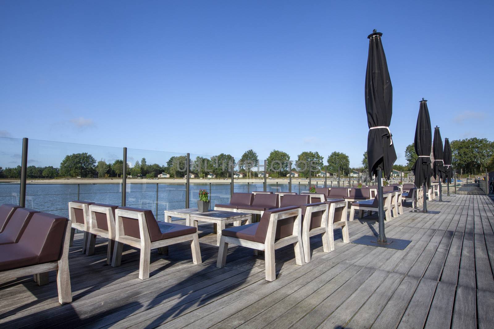 beach chair and black umbrella on the floor with lake view and a blue sky