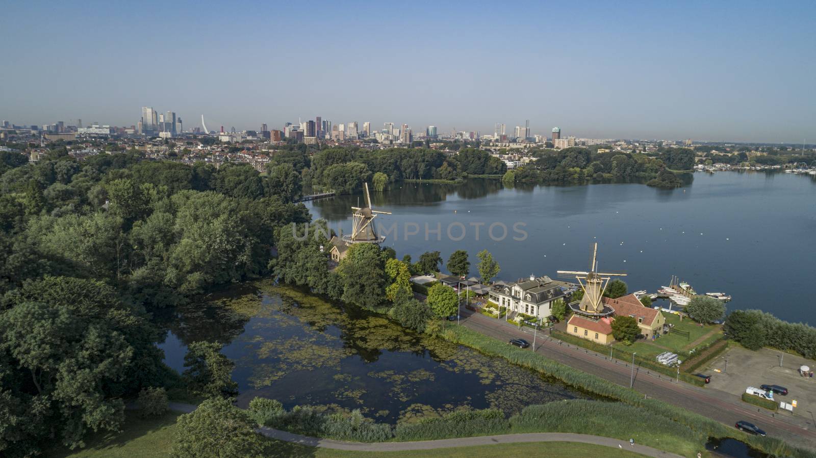 Dutch mill in early morning light. View on the skyline of Rotterdam as seen from the Kralingse Bos