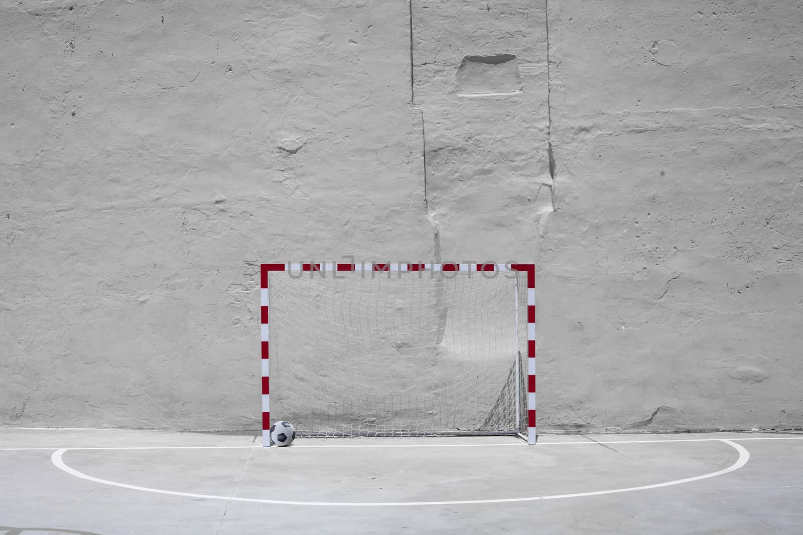 Soccer ball and goal with net against yellow plastered wall back by Tjeerdkruse