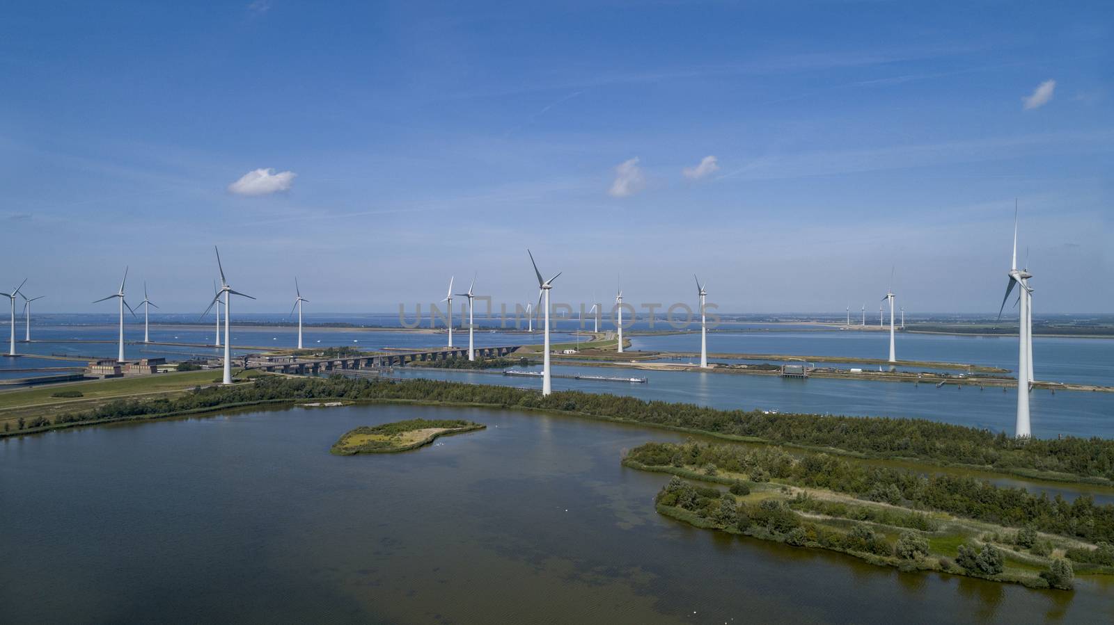 A Modern Wind Farm consisting of Wind Turbines with Two and Three Blades along the Shore of Grevelingenmeer under a Blue Sky in the Netherlands