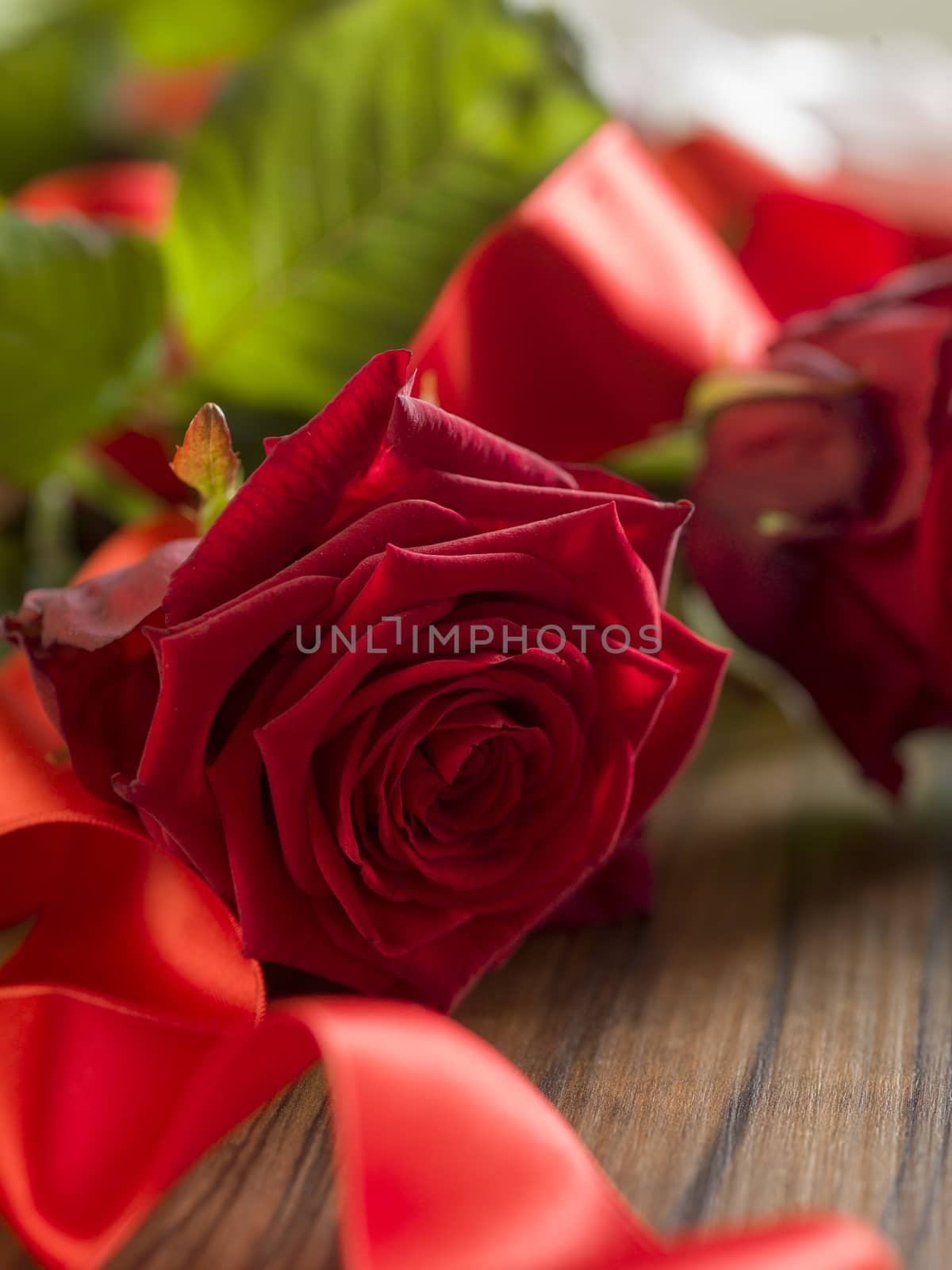 Valentine's day background with red roses and red ribbon on wood by Tjeerdkruse