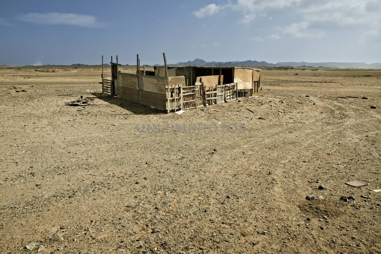 An old building in a desert landscape with mountains in the distance