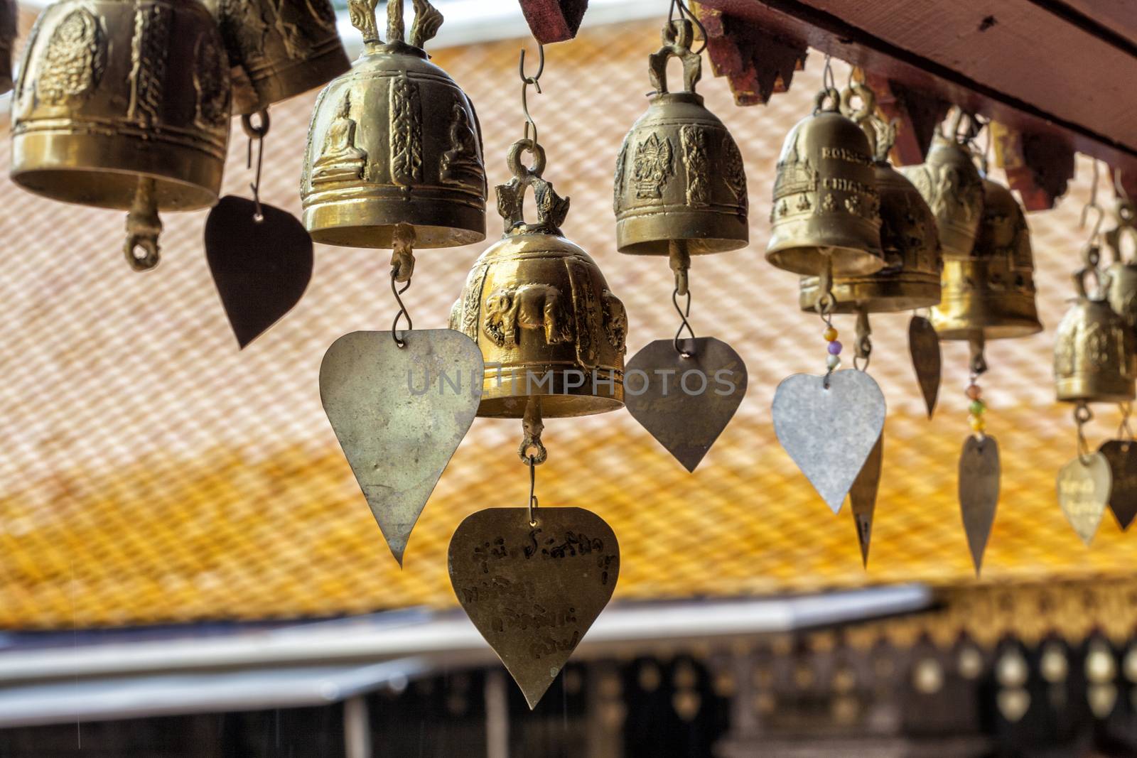 Many golden buddhist bells with wishes in sunlight by Tjeerdkruse