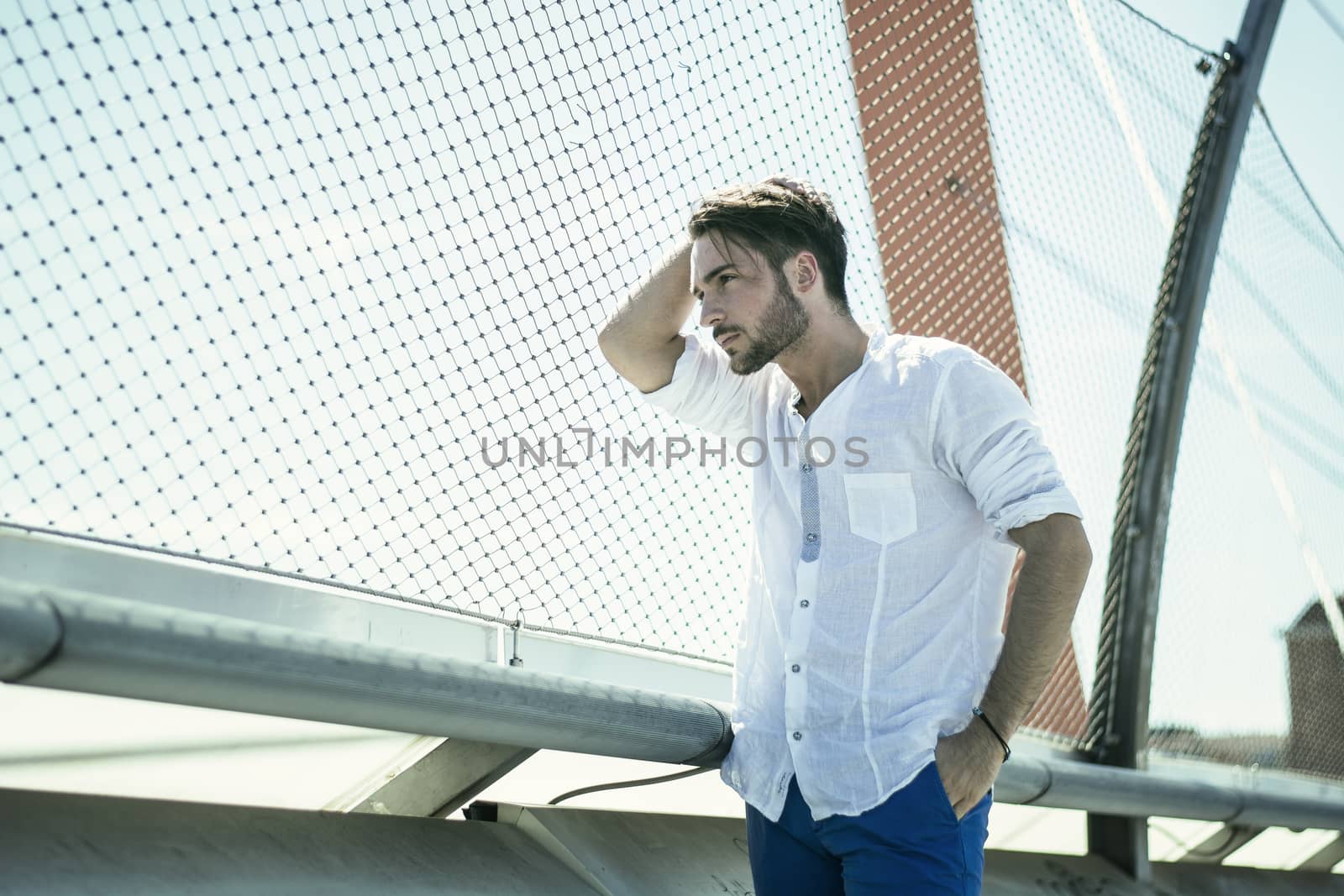 One handsome young man in urban setting in European city, standing