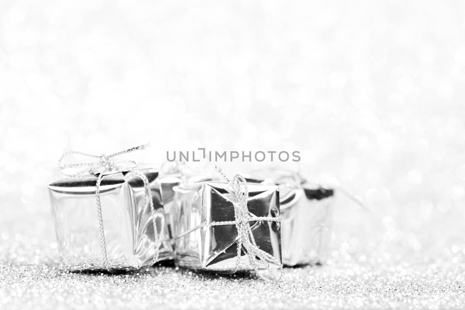 Small boxes with decorative holiday gifts on silver bokeh background