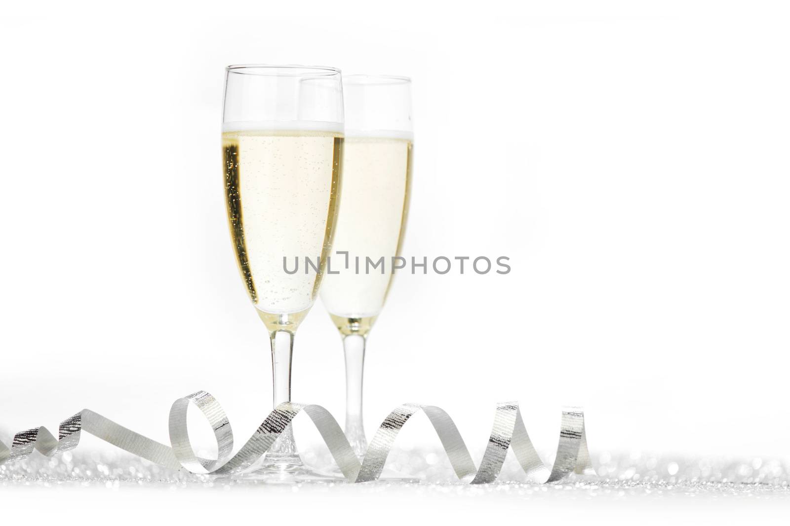 Two champagne glasses and silver shiny glitters isolated on white background
