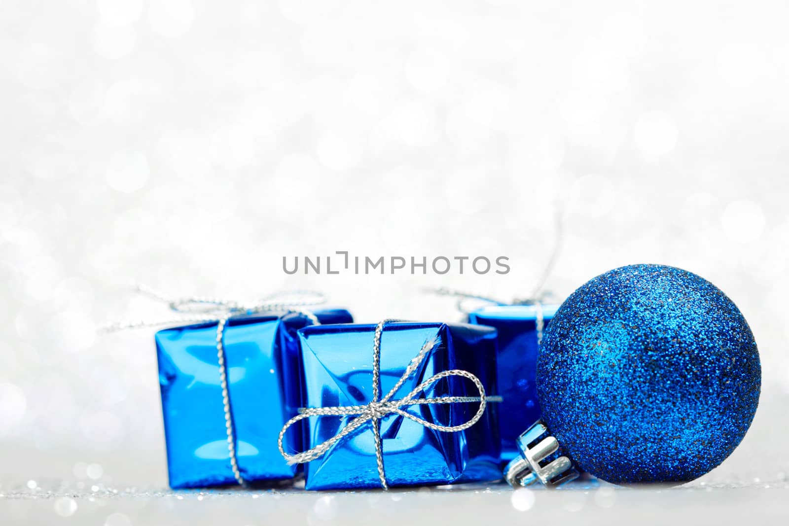 Decorative Christmas ball and gifts on abstract glitter silver background