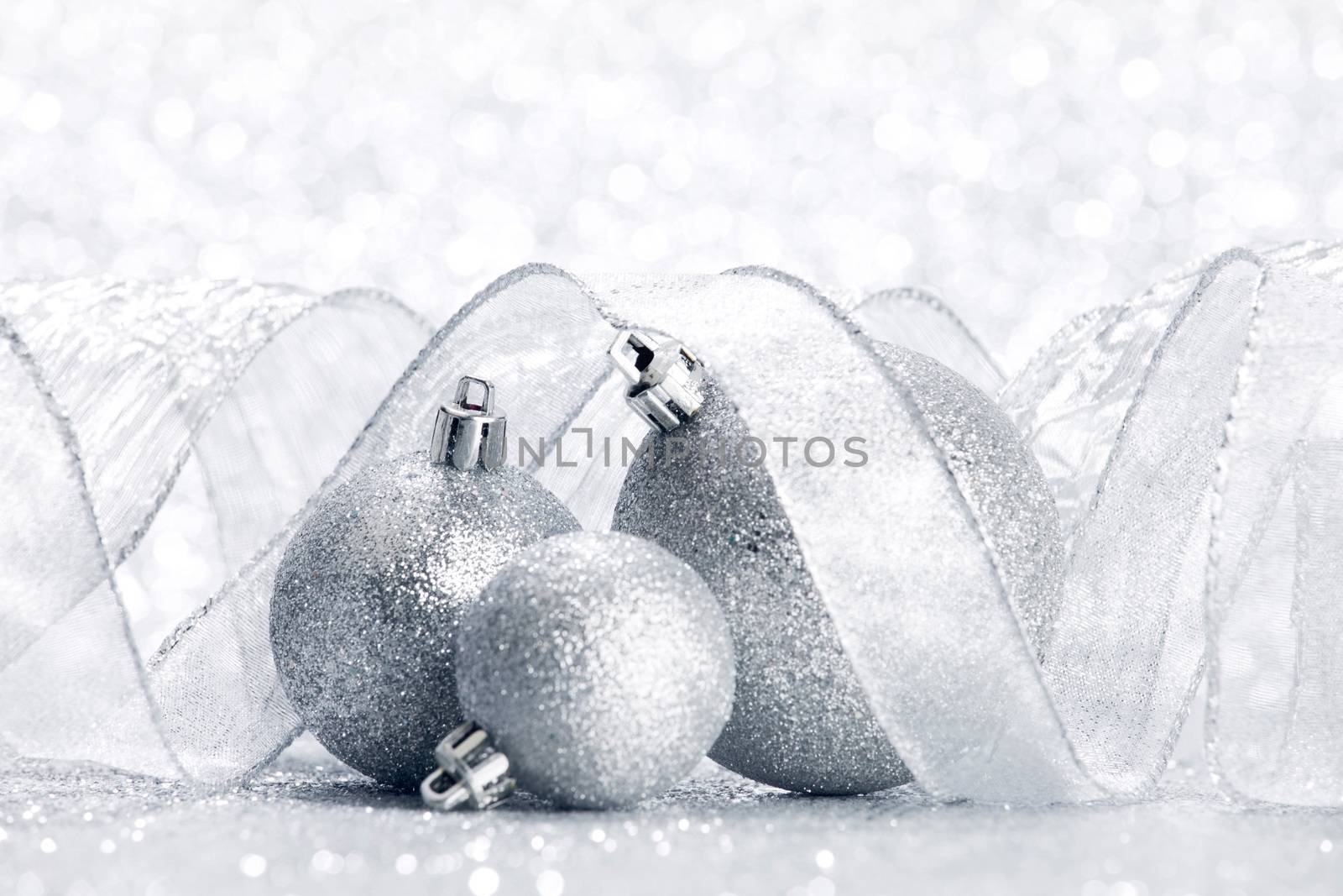 Christmas decorative balls and ribbon on silver glitter background