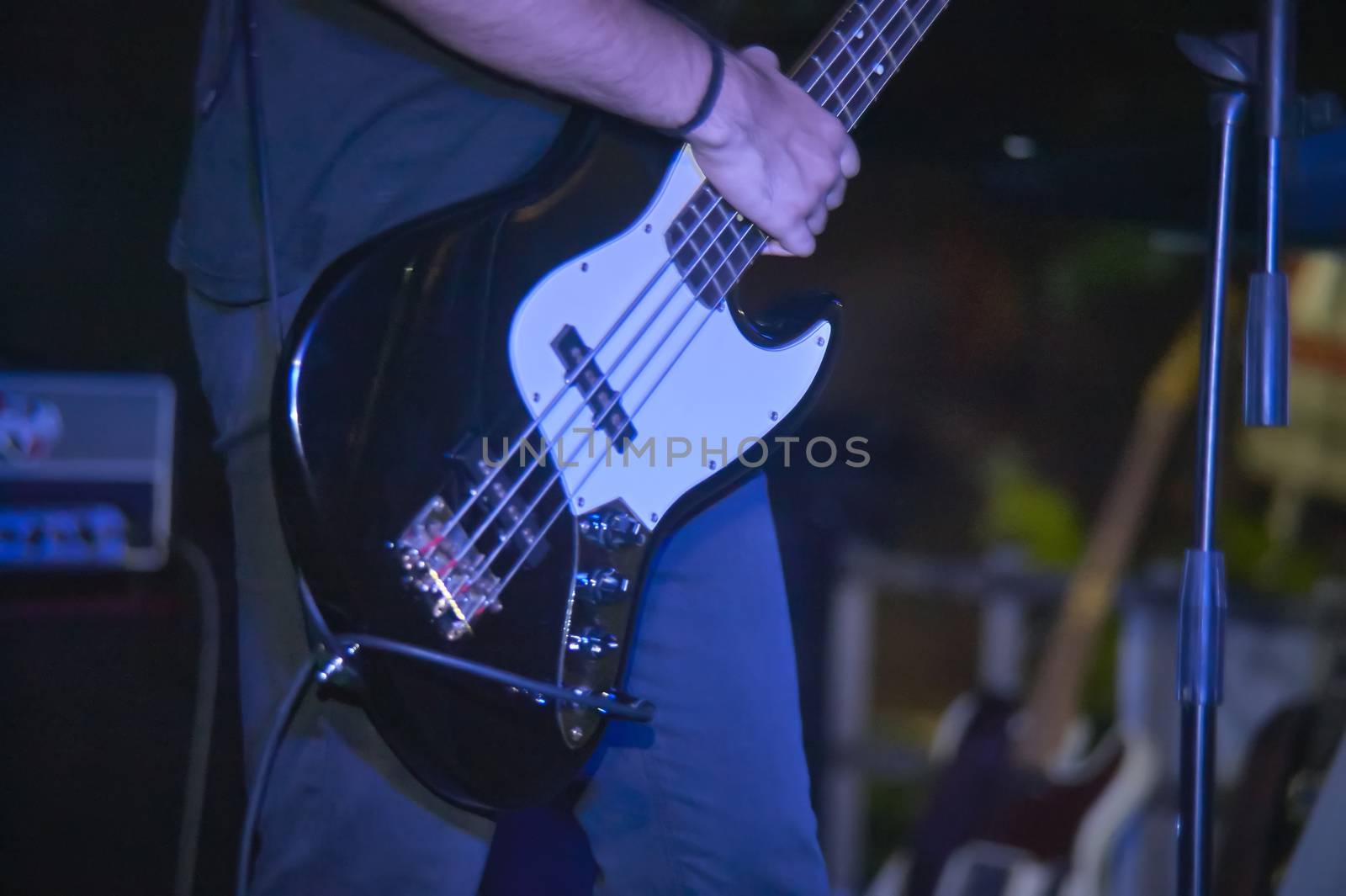 Detail of a bass player who plays his eacoustica bass at a live rock music concert.