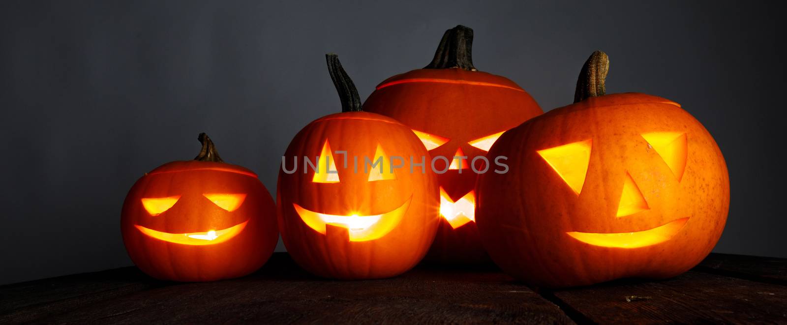Halloween pumpkin head jack o lantern and candles on gray background