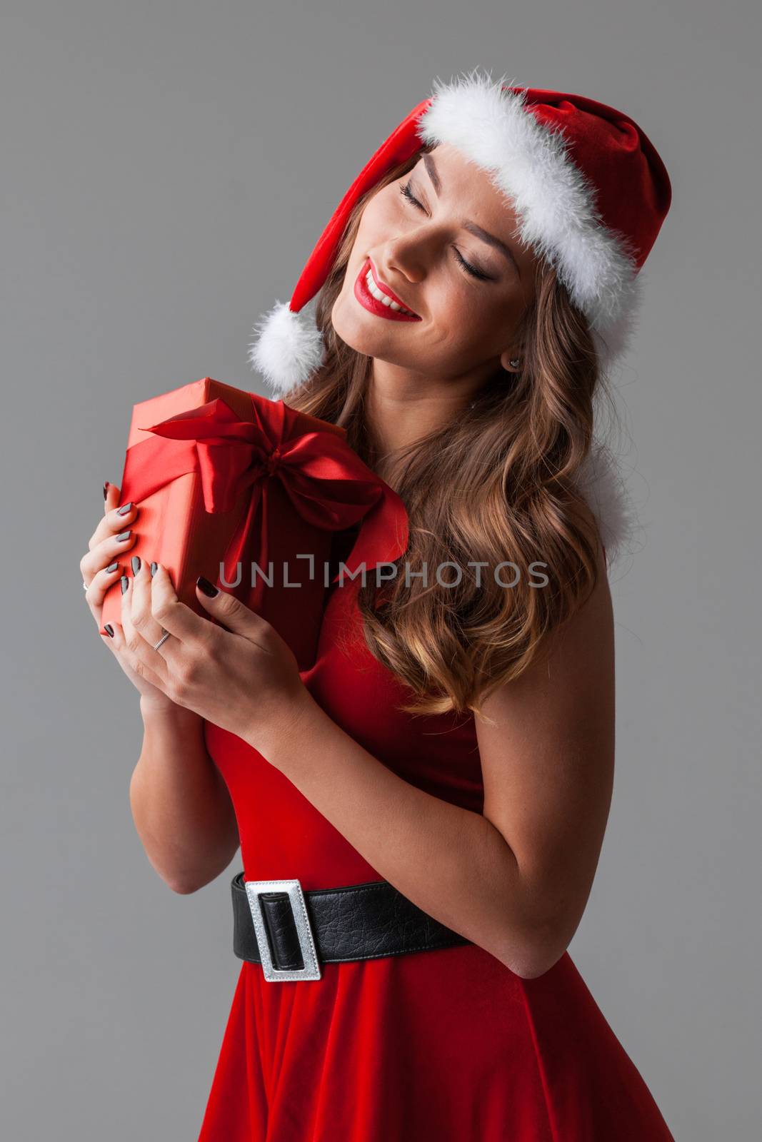 Beautiful hispanic woman in red santa claus costume holding Christmas gift