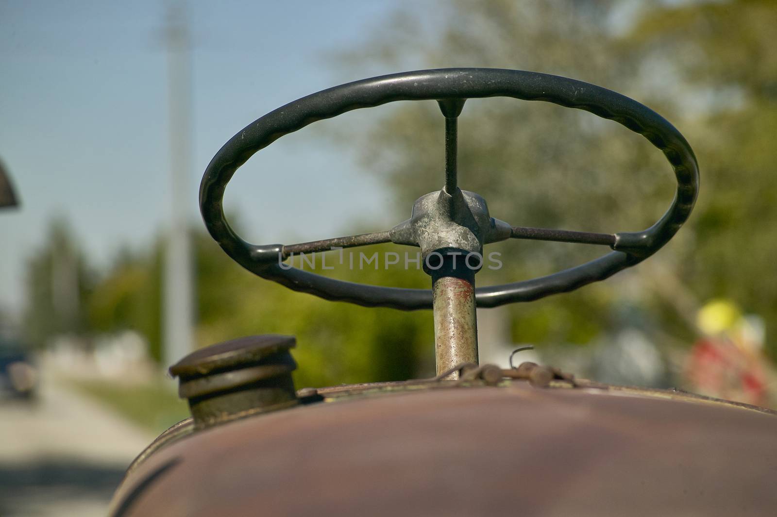 Details of the steering wheel and instrumentation of an old farm tractor nestled in the countryside during a work day.