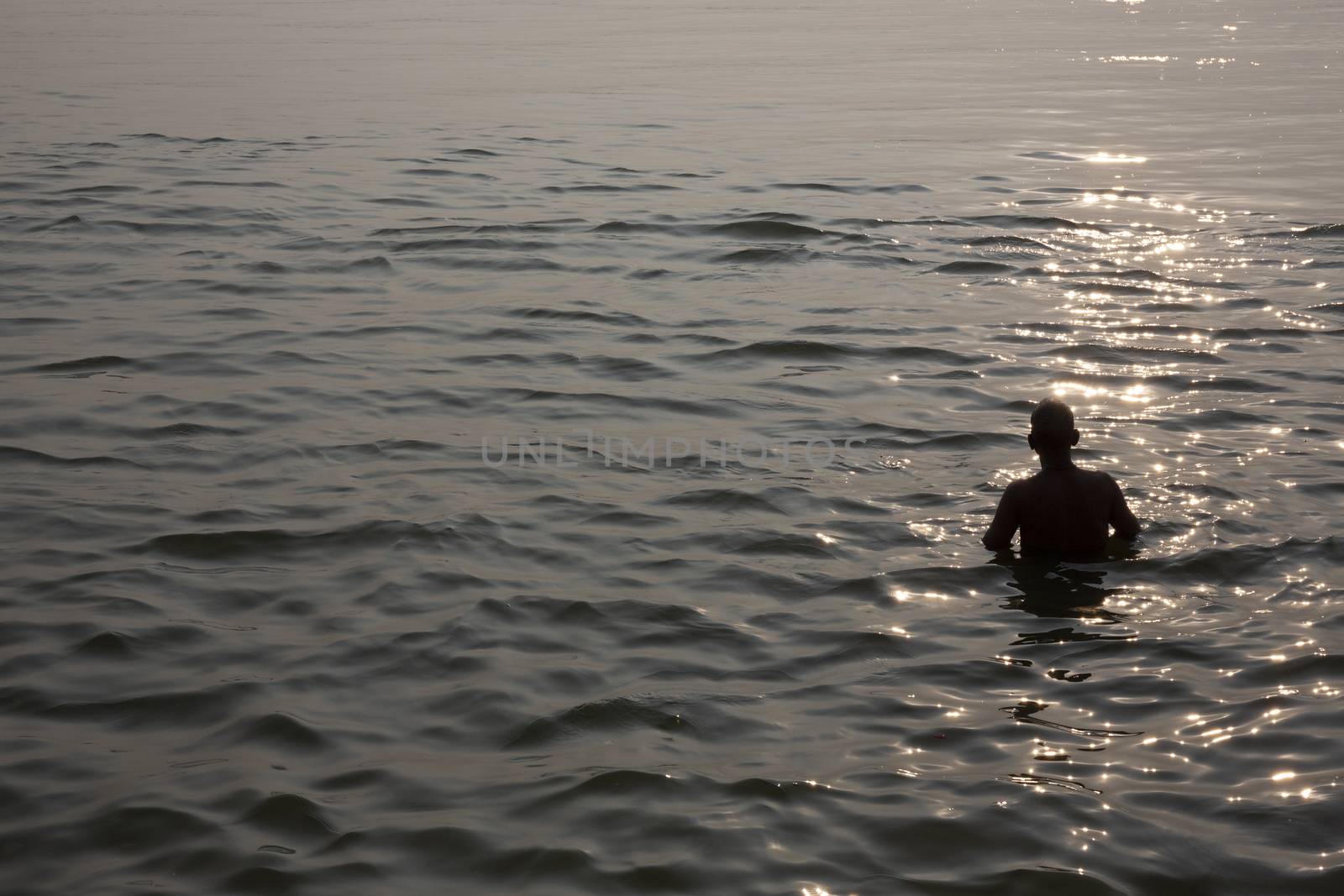 Silhouette of a man taking bath in ganges river during sunset by Tjeerdkruse