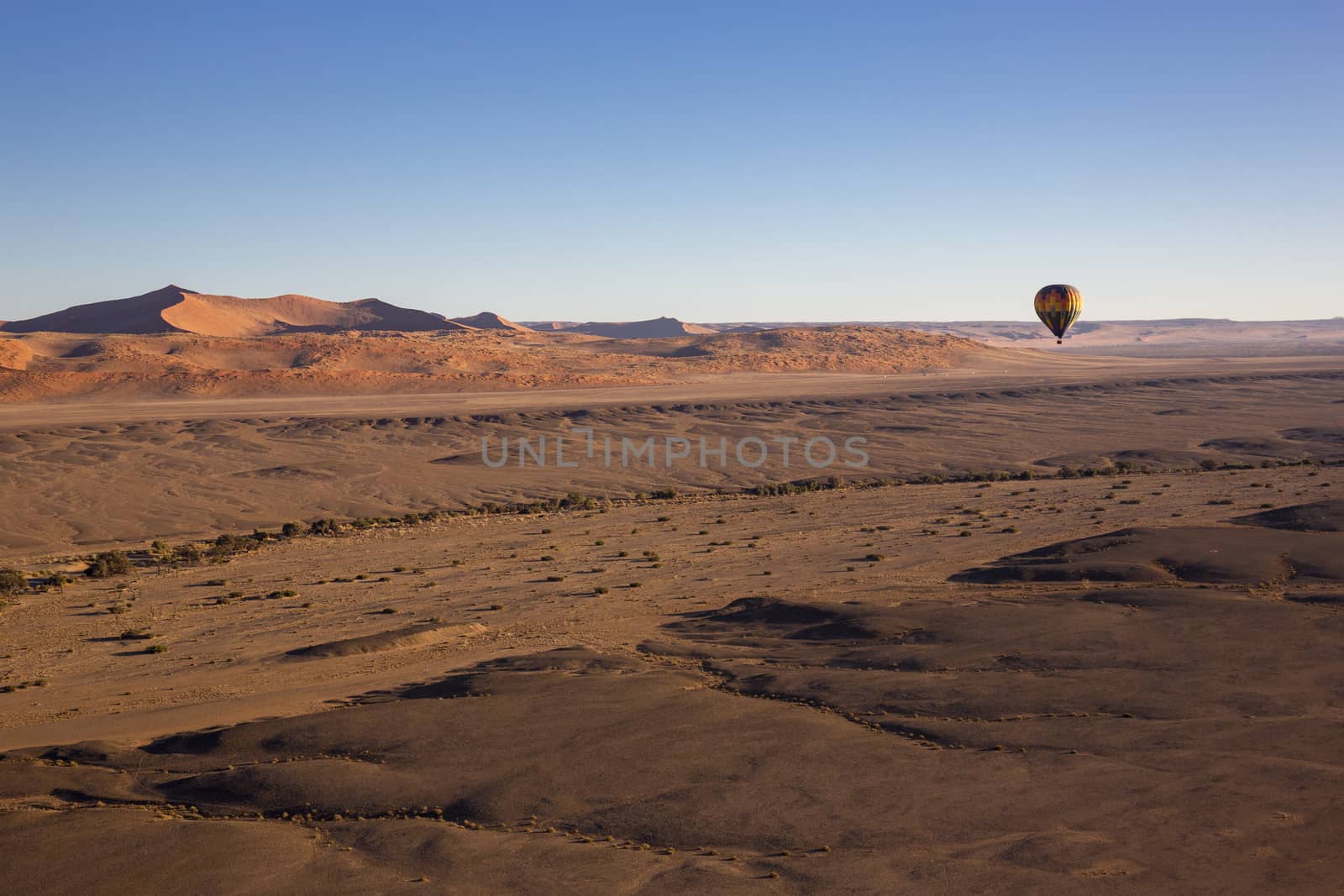 Sossusvlei. Colorful hot-air balloon flying over the high mountains in Namibia. High altitude. (Namibia, South Africa)