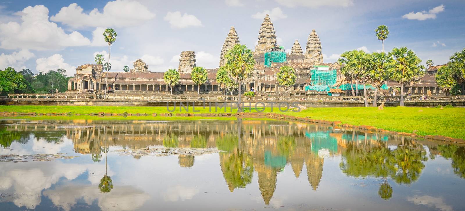 Angkor Wat temple complex reflection on the lake under summer cloud blue sky. Ancient Khmer architecture in Cambodia and is the largest religious monument in the world.