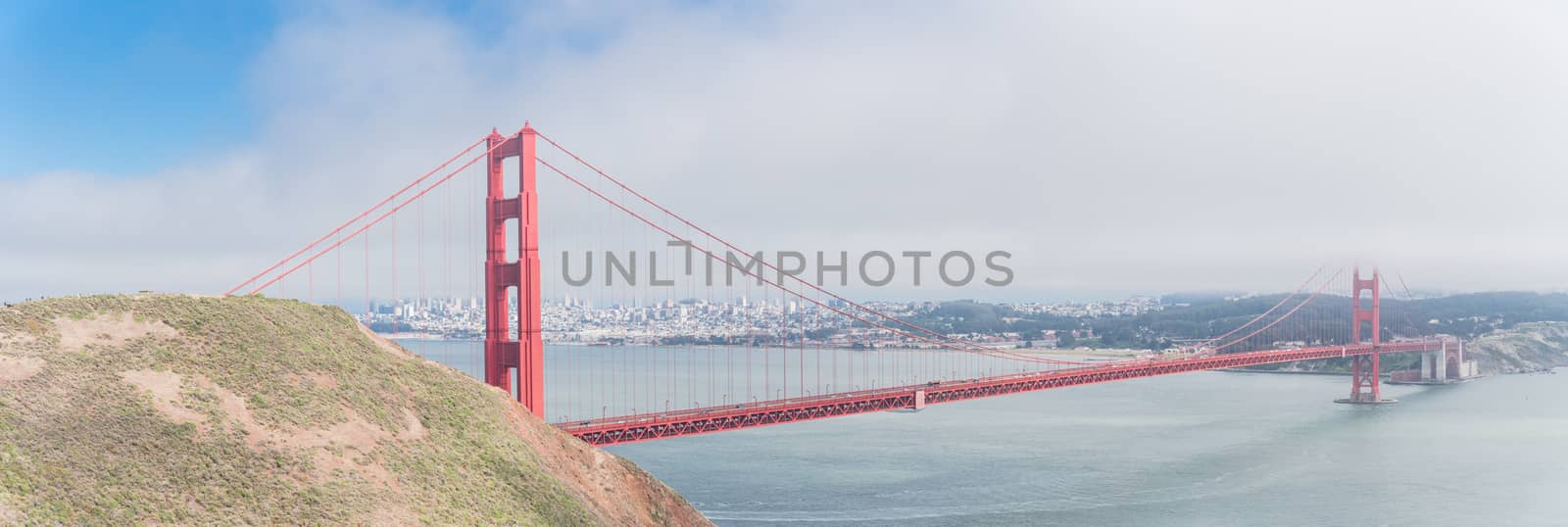 Battery Kirby ridge toward Batter Wagner view of Golden Gate Bridge. Panorama of iconic San Francisco travel destination with downtown in background, summer foggy day.