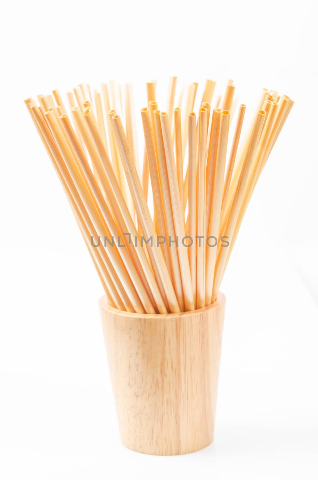 Wheat straw for drinking water in wooden glass on white background. Zero waste concept.