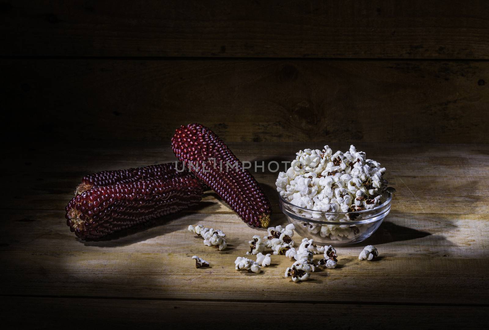 Popcorn in glass bowl over wooden background