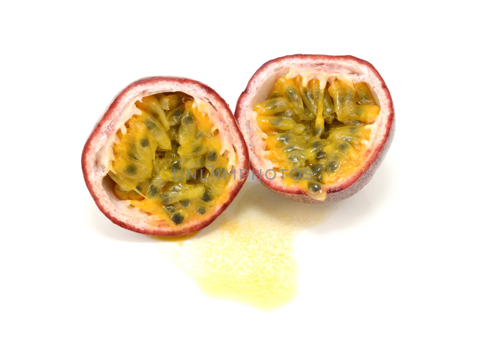 Passion fruit cut in half to reveal juicy yellow pulp around seeds, on a white background