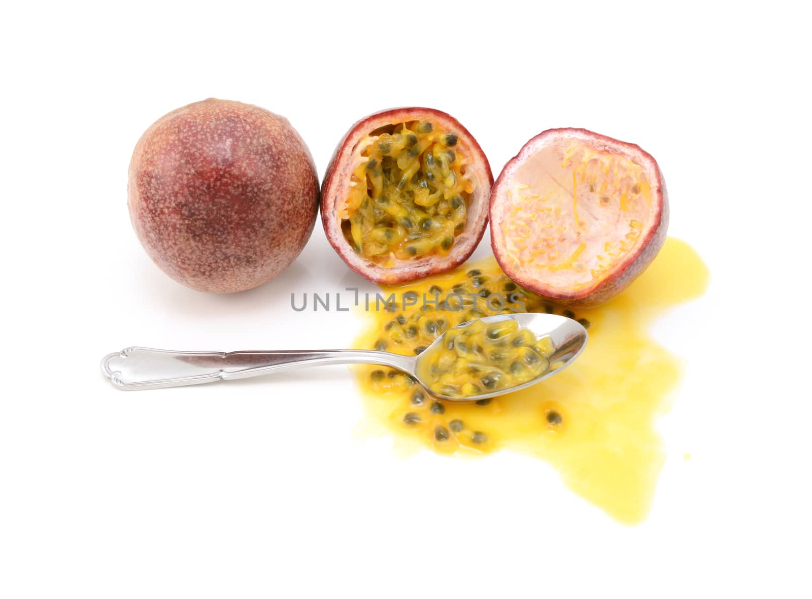 Whole and halved passion fruits ready to eat with a spoon, with spilled juice and sweet seeds, on a white background 