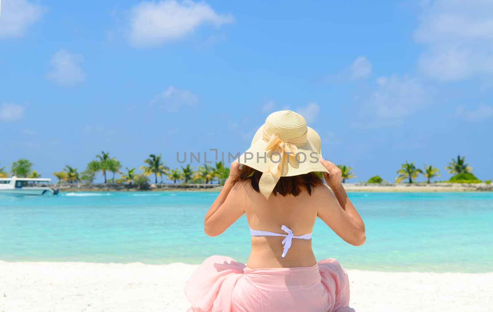 Beautiful asian young woman in sunhat sitting relaxed on sand, tropical beach in Maldives