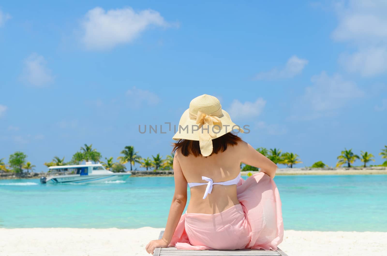 Beautiful asian young woman in sunhat sitting relaxed on sand, tropical beach in Maldives