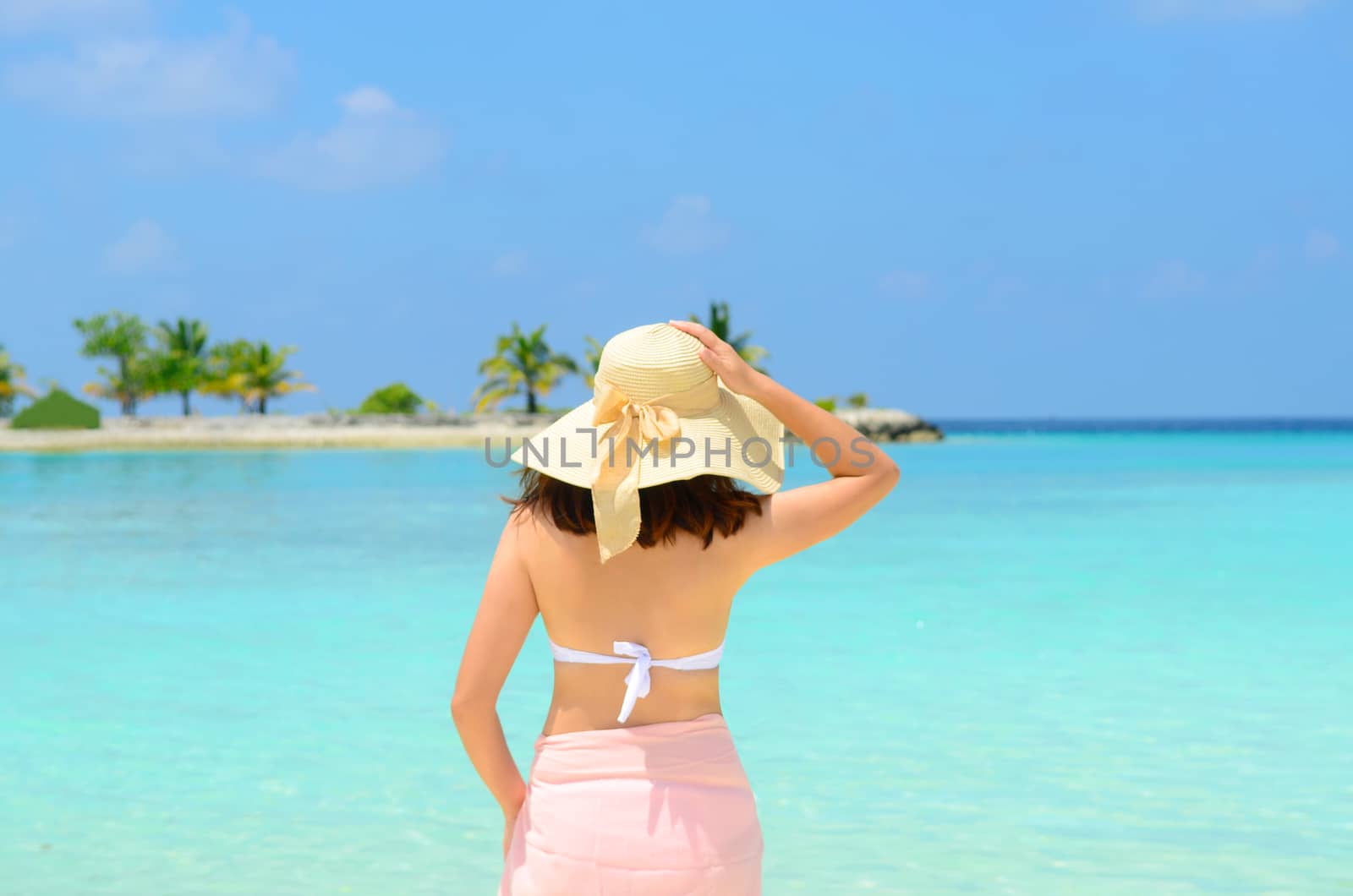 Beautiful asian young woman in sunhat  relaxed at tropical beach in Maldives