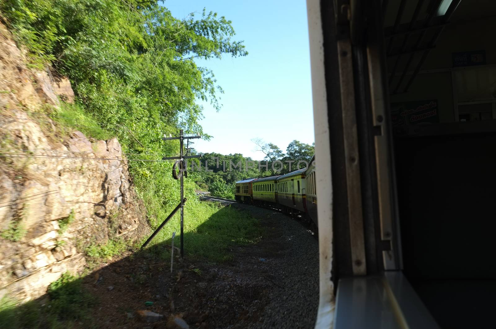 View from train railway makes a curve bend through beautiful natural green grasslands and mountains . Travel in Thailand