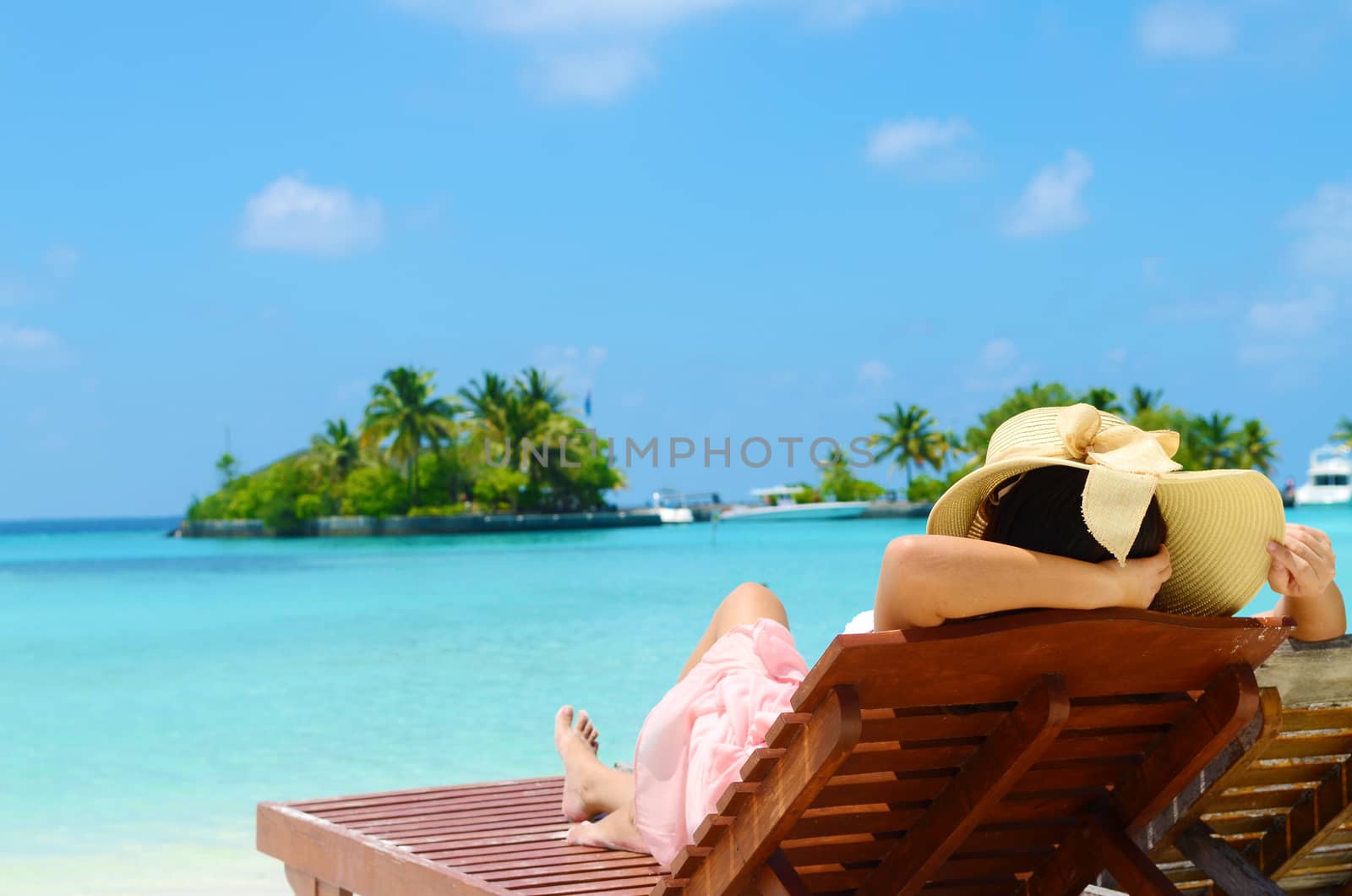 Woman on sunbed relaxing  at tropical  Maldives island. Travel and Vacation.