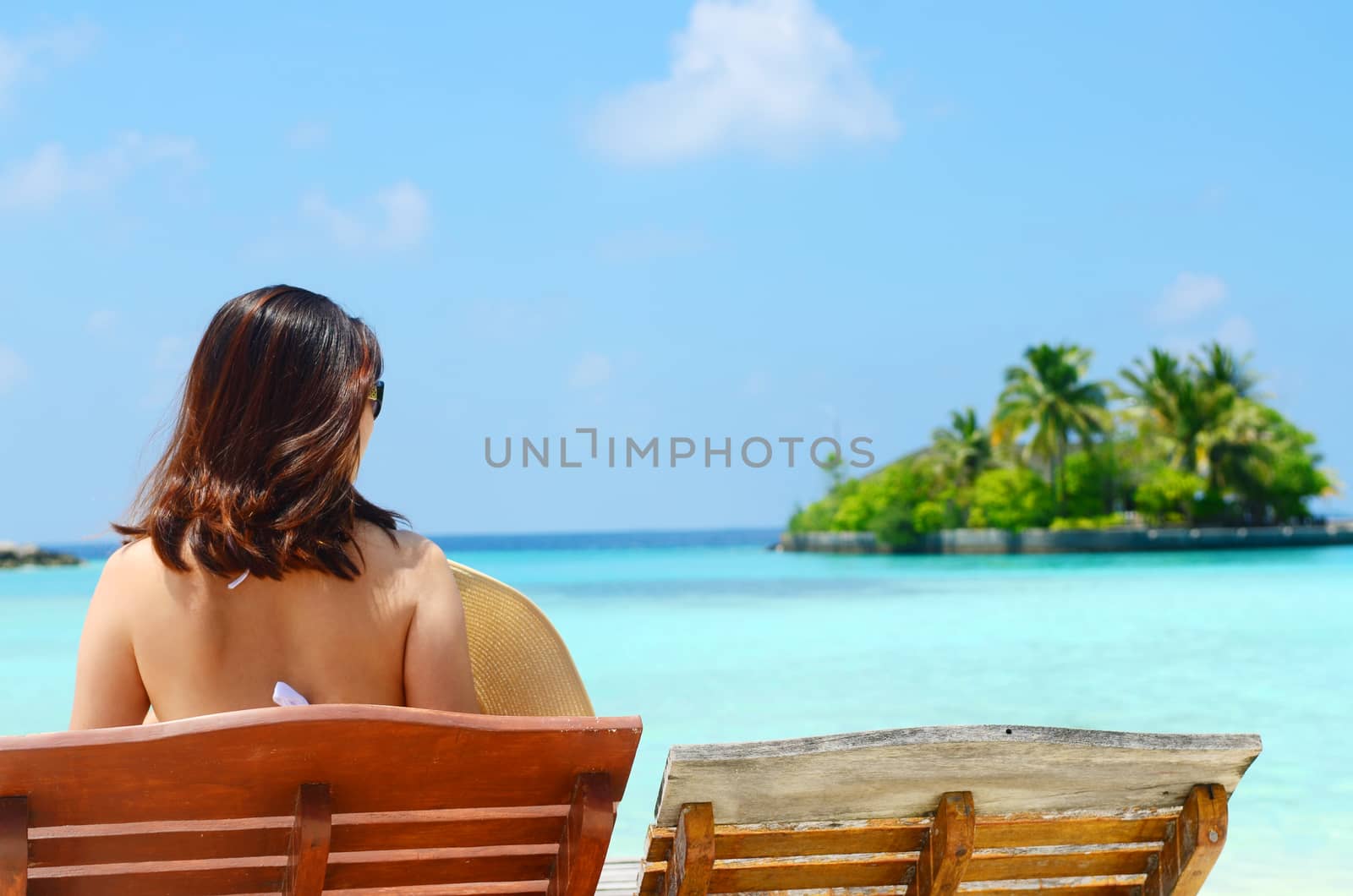 Woman on sunbed relaxing  at tropical  Maldives island. Travel and Vacation. 