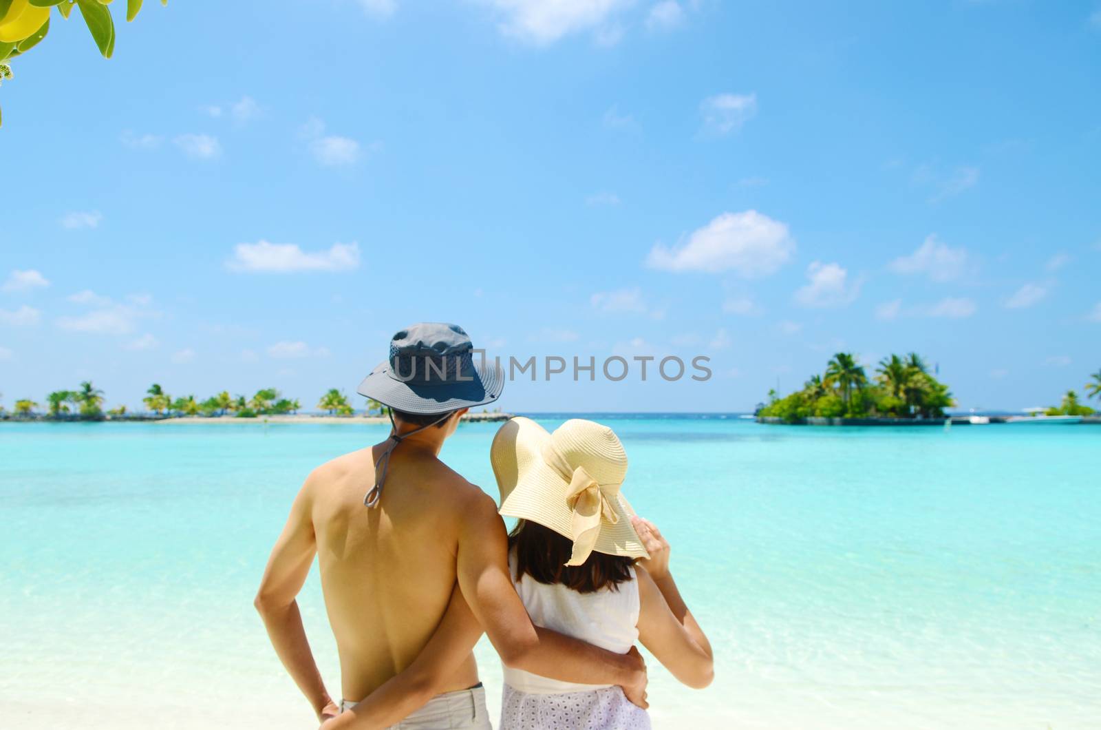 Young happy asian couple  in sunhat on white beach at summer vacation in Maldives island