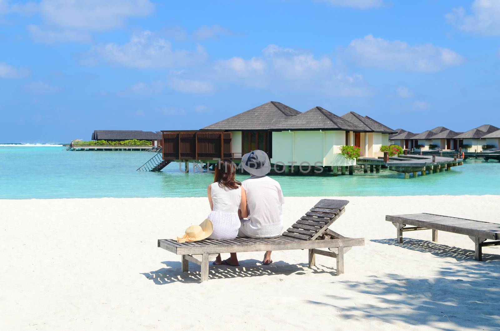 Asian couple on a tropical beach jetty at water resort,Maldives