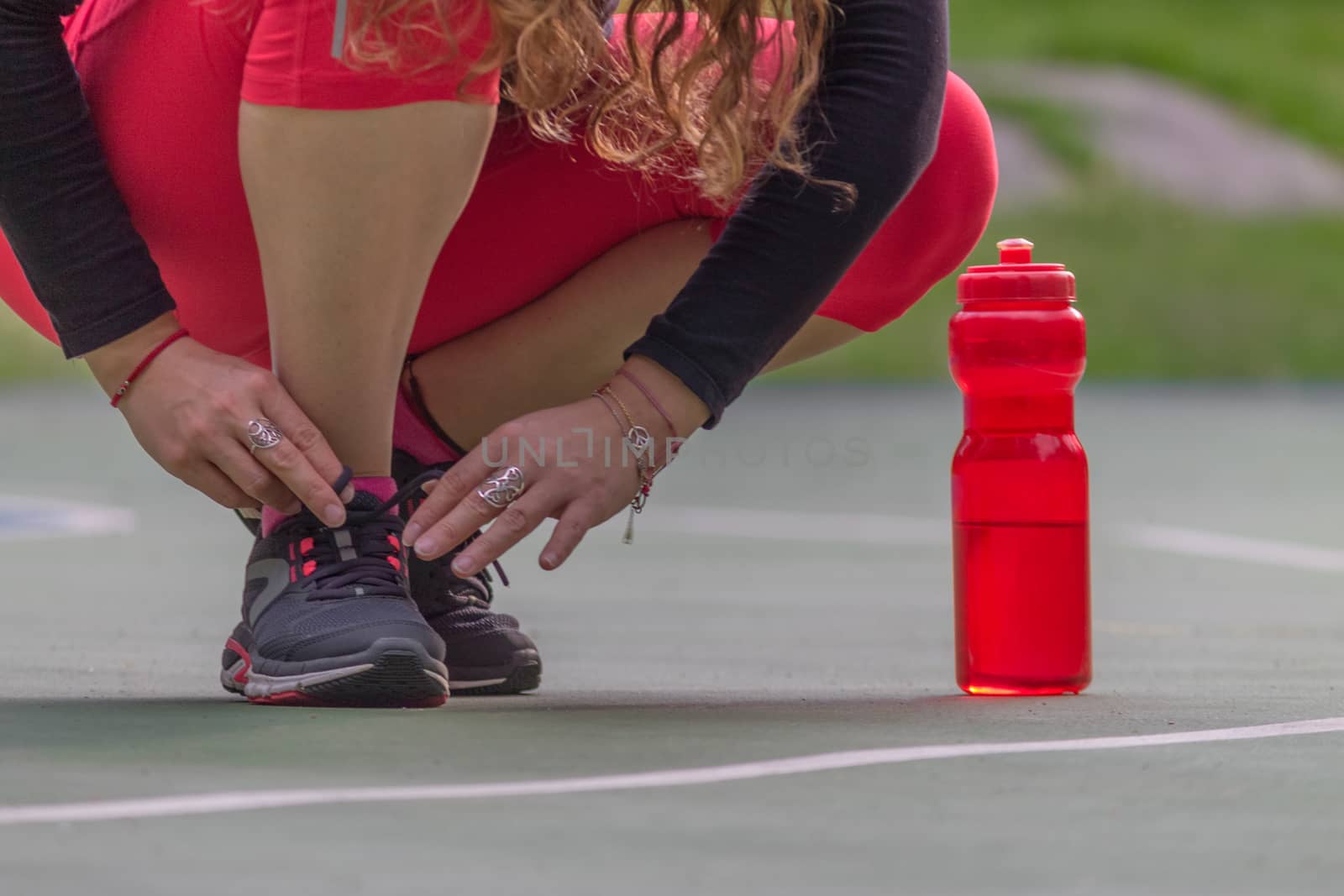 Woman adjusting her tennis shoes by leo_de_la_garza