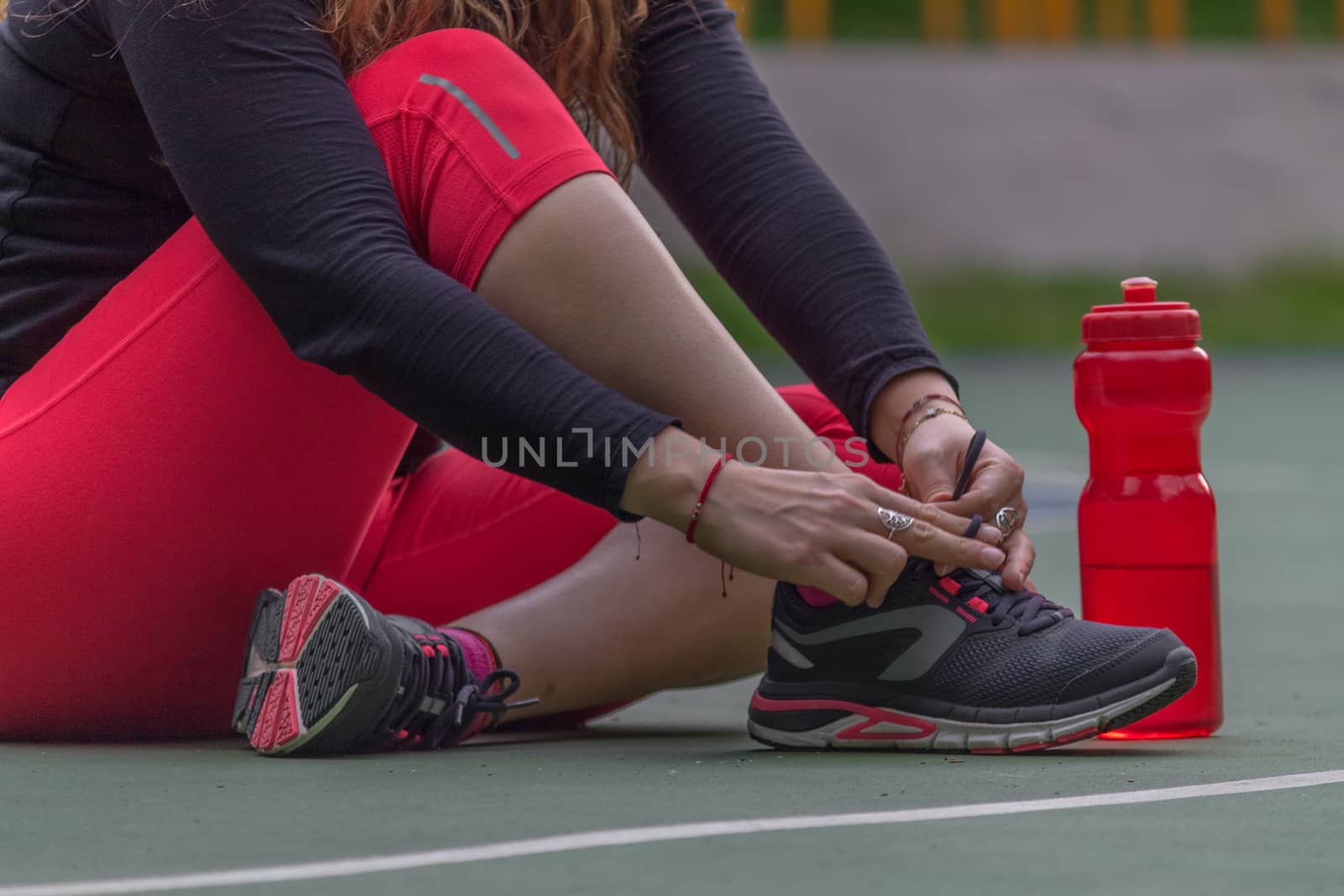 Woman adjusting her tennis shoes by leo_de_la_garza