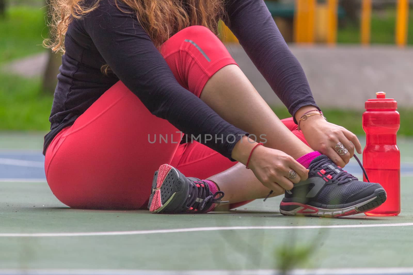 Woman adjusting her tennis shoes by leo_de_la_garza