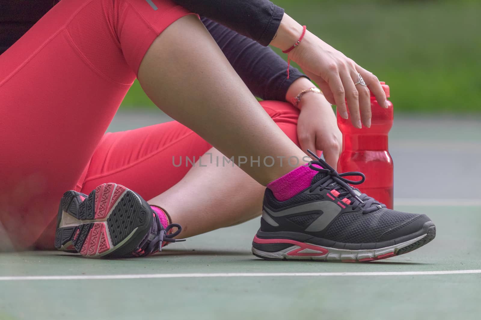Woman adjusting her tennis shoes by leo_de_la_garza