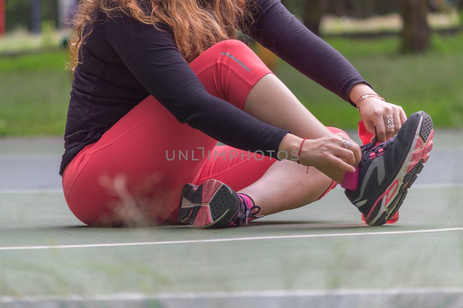 Woman adjusting her tennis shoes by leo_de_la_garza