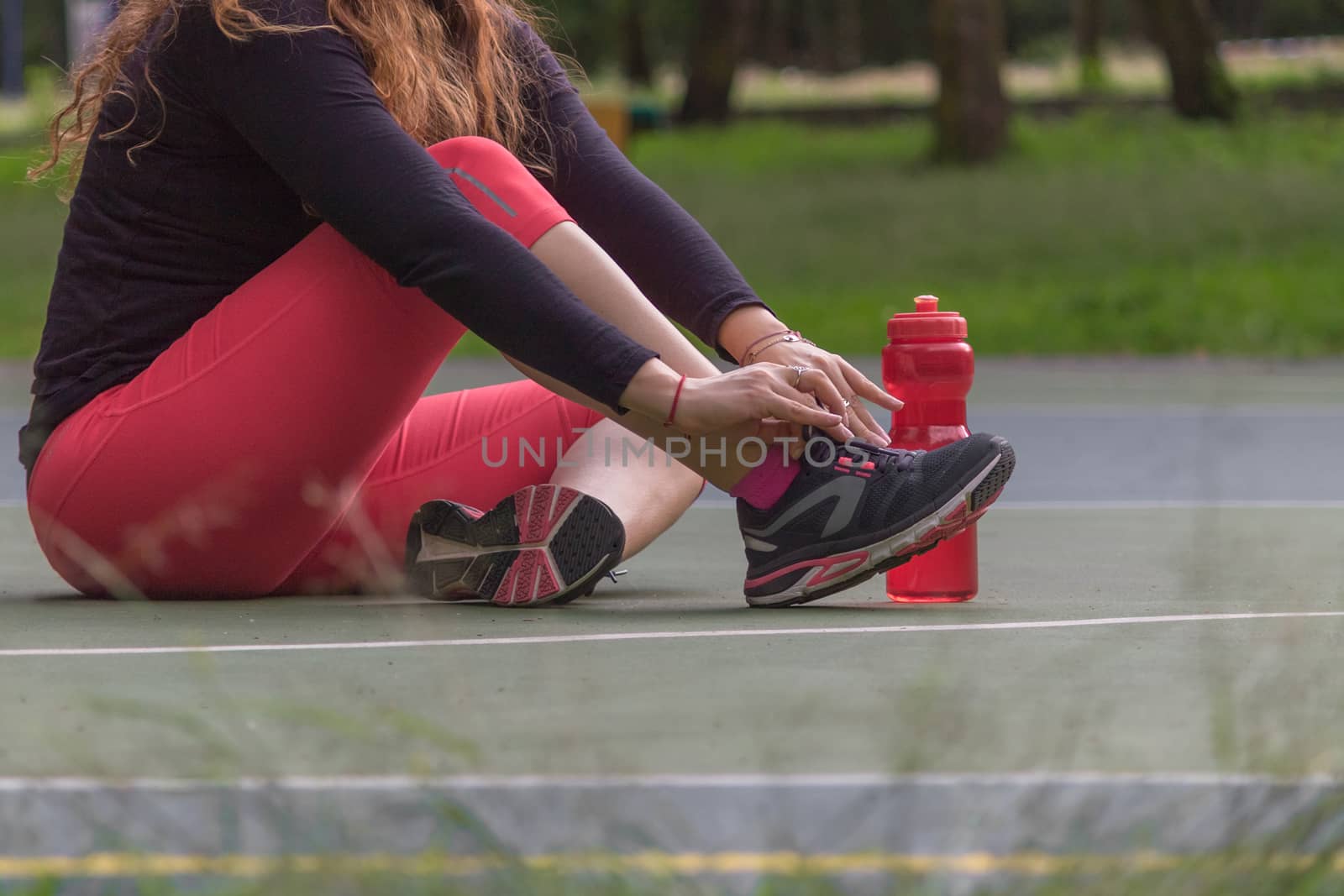 Woman adjusting her tennis shoes by leo_de_la_garza