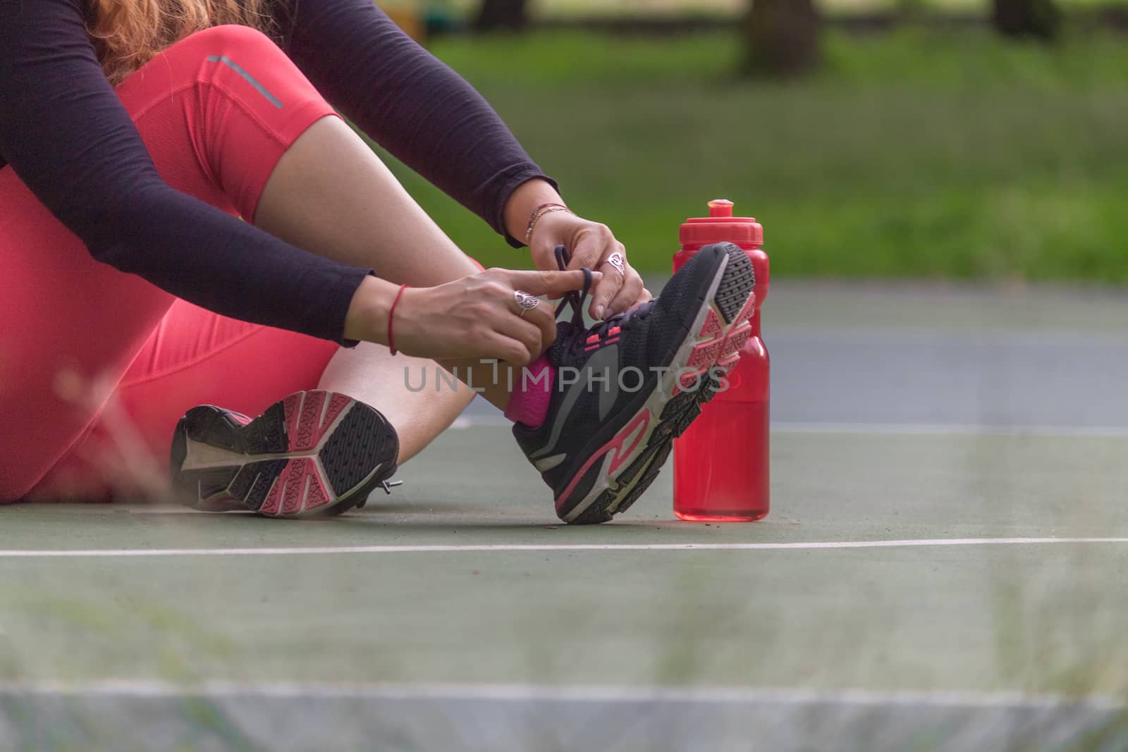 Woman adjusting her tennis shoes by leo_de_la_garza