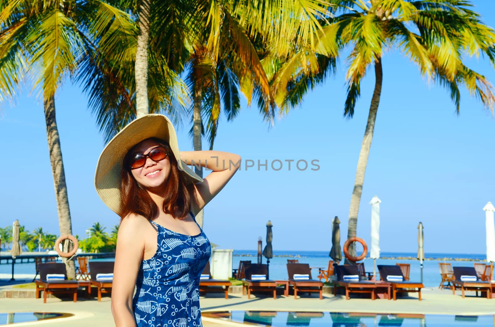 Beautiful asian woman in sunhat relaxed at tropical beach in Maldives.Holiday and travel concept.