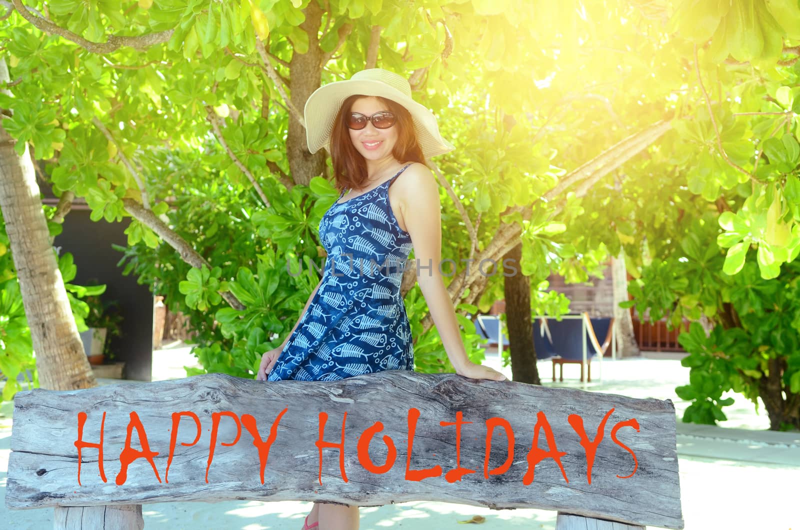 Potrait of a beautiful young asian girl in sunhat with long hair on a background of tree and sand on beach on a sunny day, lifestyle, posing and smiling.