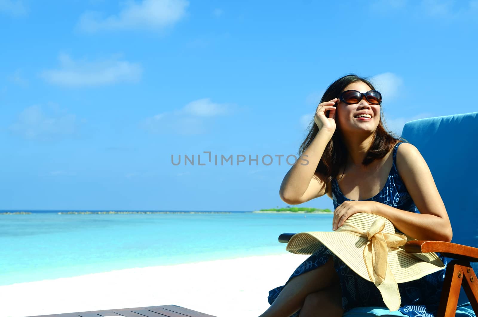 close-up portrait of a beautiful young asian girl with long hair on a background of blue sea and sky with clouds on a sunny day, lifestyle, posing and smiling.