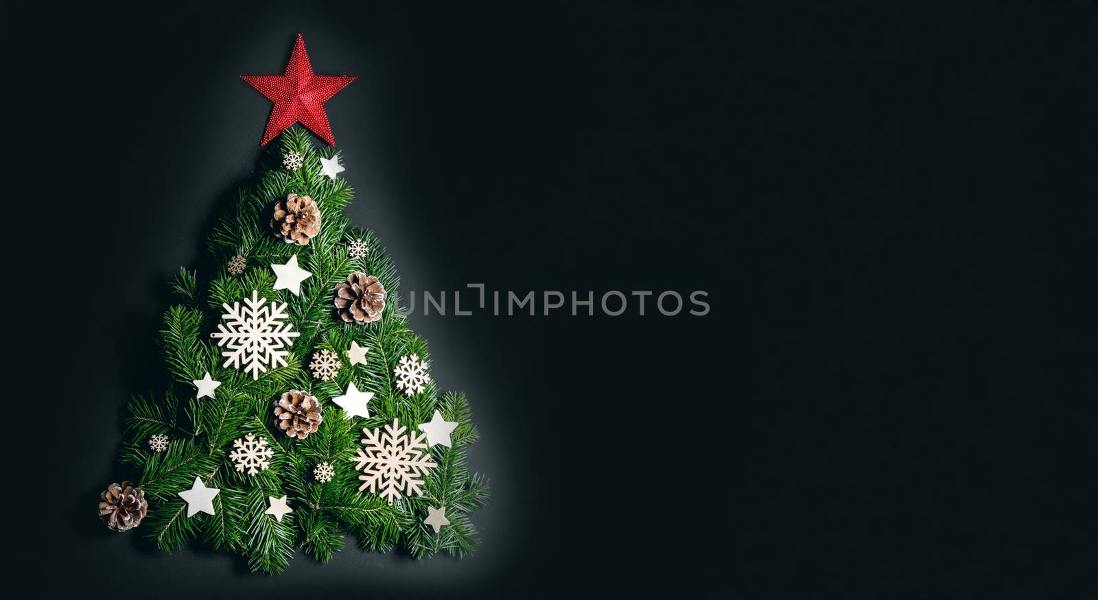 Christmas tree made of natural spruce branches deecor with red star on black background, flat lay card with copy space