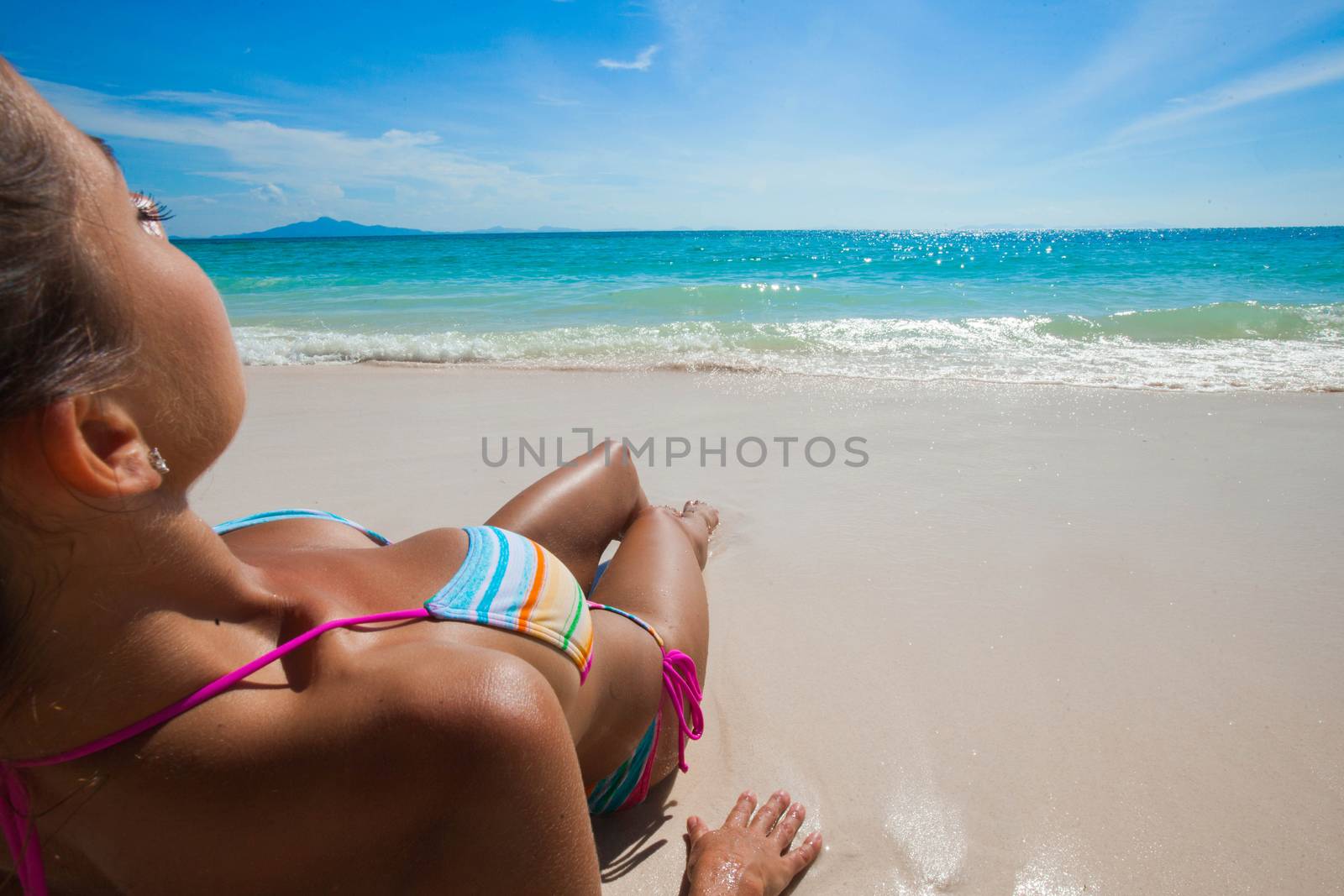 Young woman in bikini laying at seaside, rear view