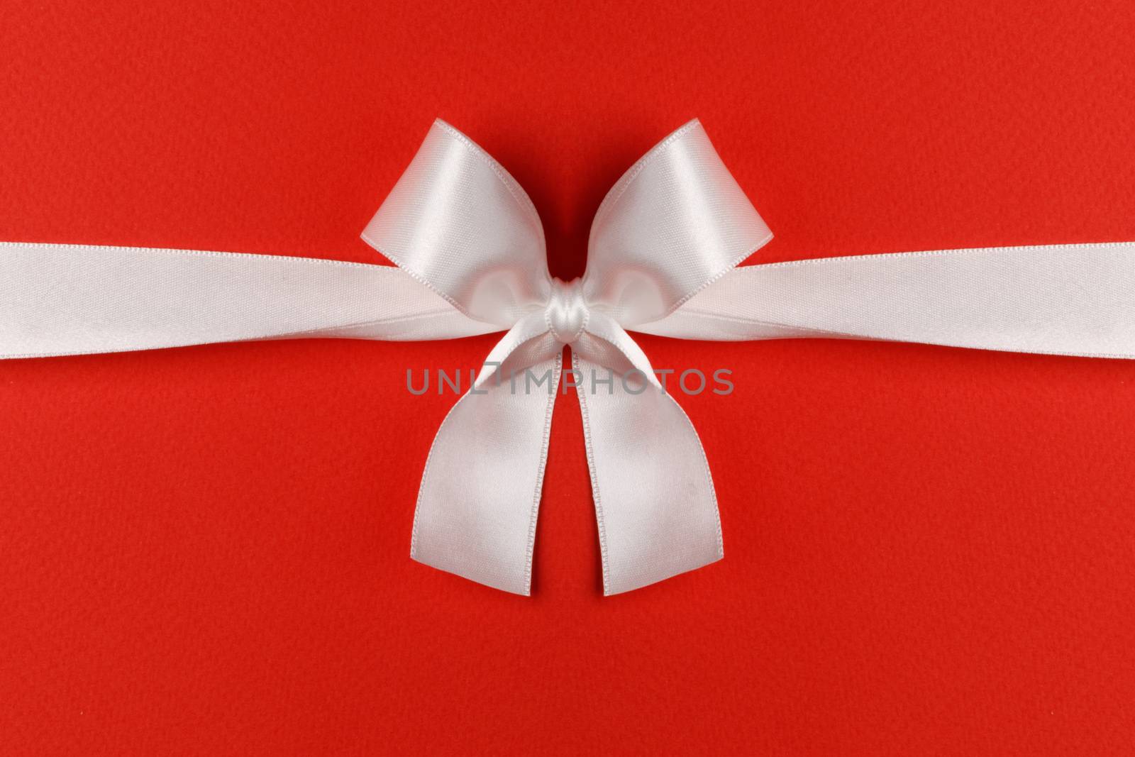 White gift bow on red background copy space for text