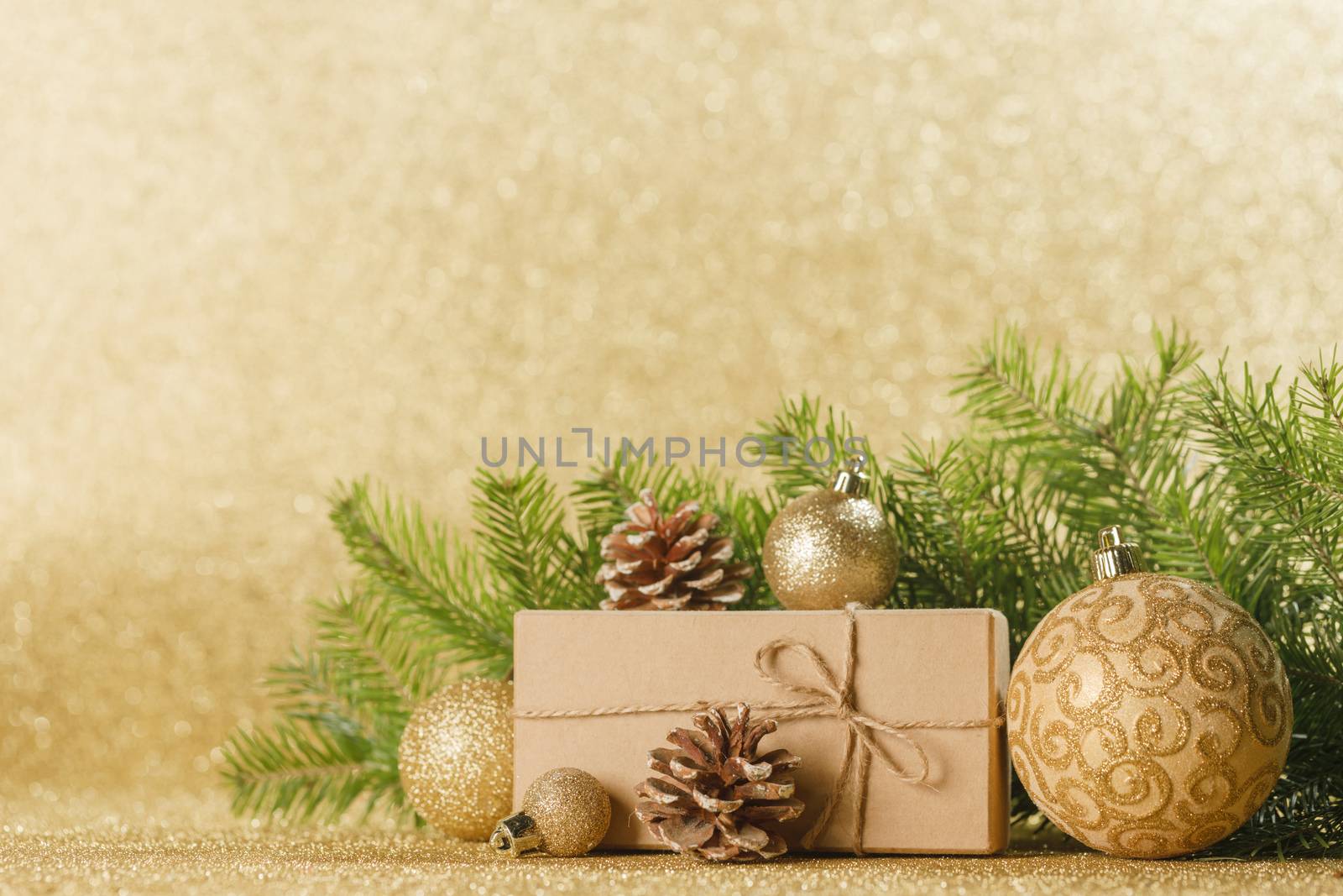 Christmas toys, decorations, present gift box wrapped in kraft paper on golden glitter background, copy space