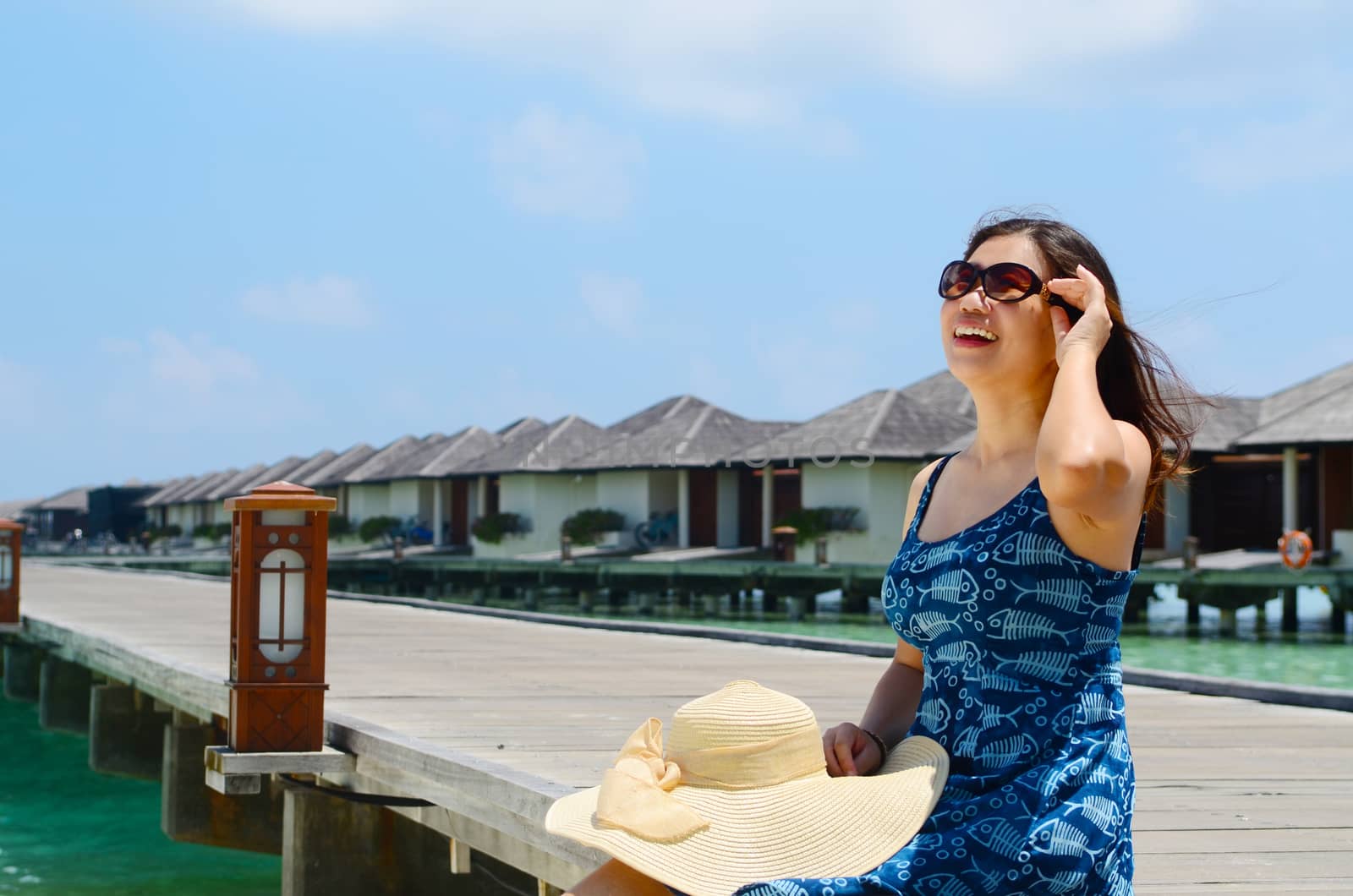 close-up portrait of a beautiful asian girl with long hair on a background of blue sea and sky with clouds on a sunny day, lifestyle, posing and smiling.